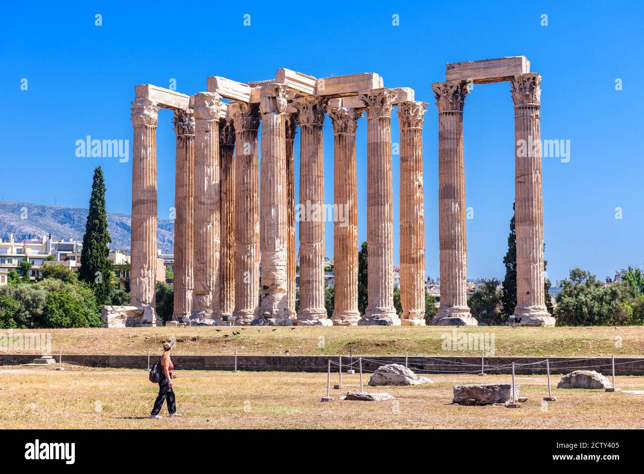 Zeus temple in summer, Athens, Greece. It is one of top landmarks of Athens. Tourist walks past majestic Ancient Greek ruins. Great columns of famous Stock Photo