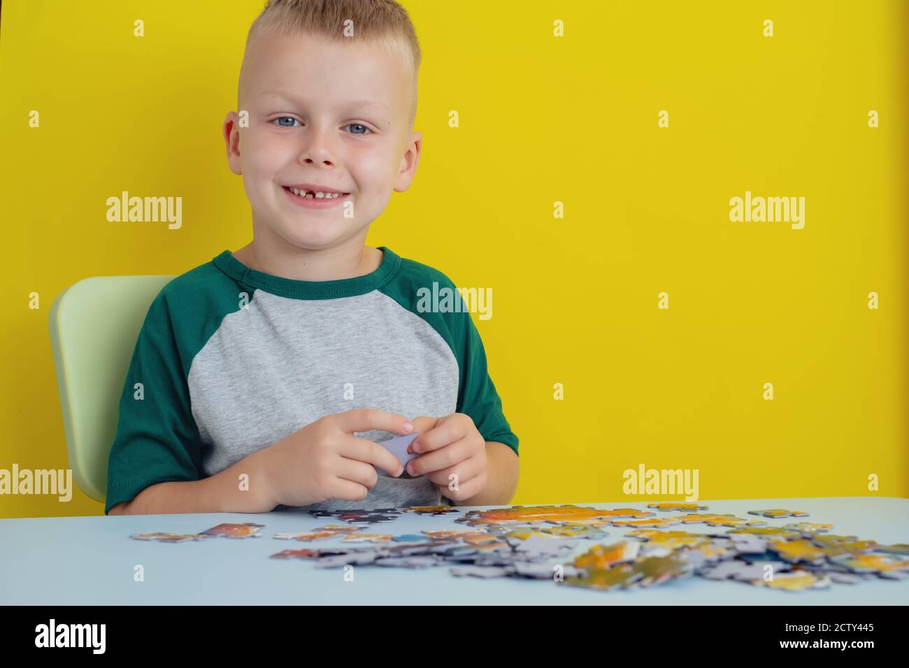 kid sitting at the table and putting together puzzles. Early learning