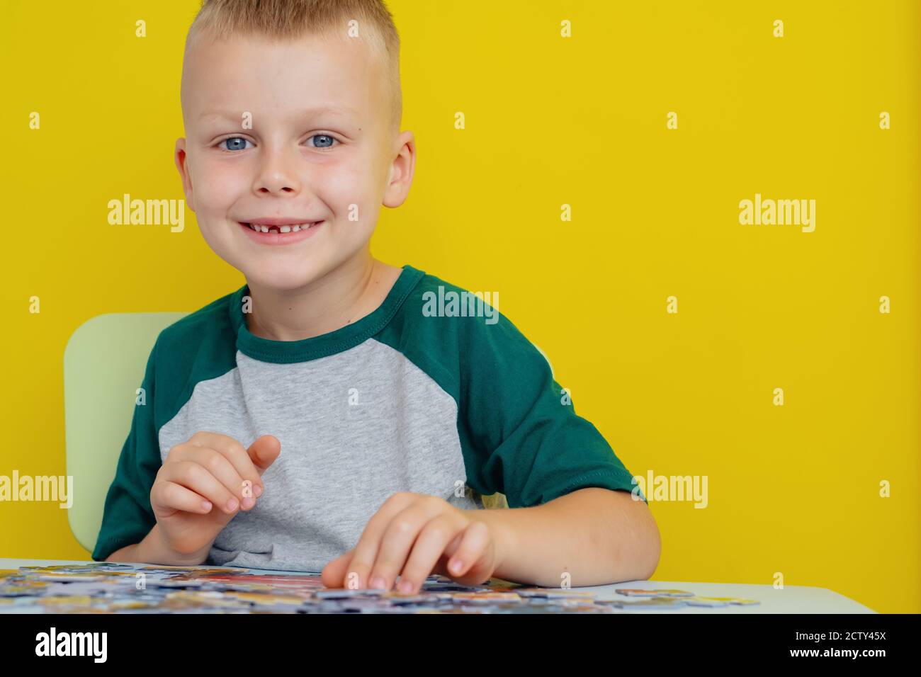 kid sitting at the table and putting together puzzles. Early learning