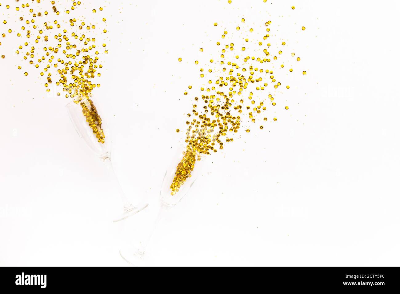 Champagne glasses with golden confetti tinsel on white background. Flat lay, top view celebrate party concept. Stock Photo