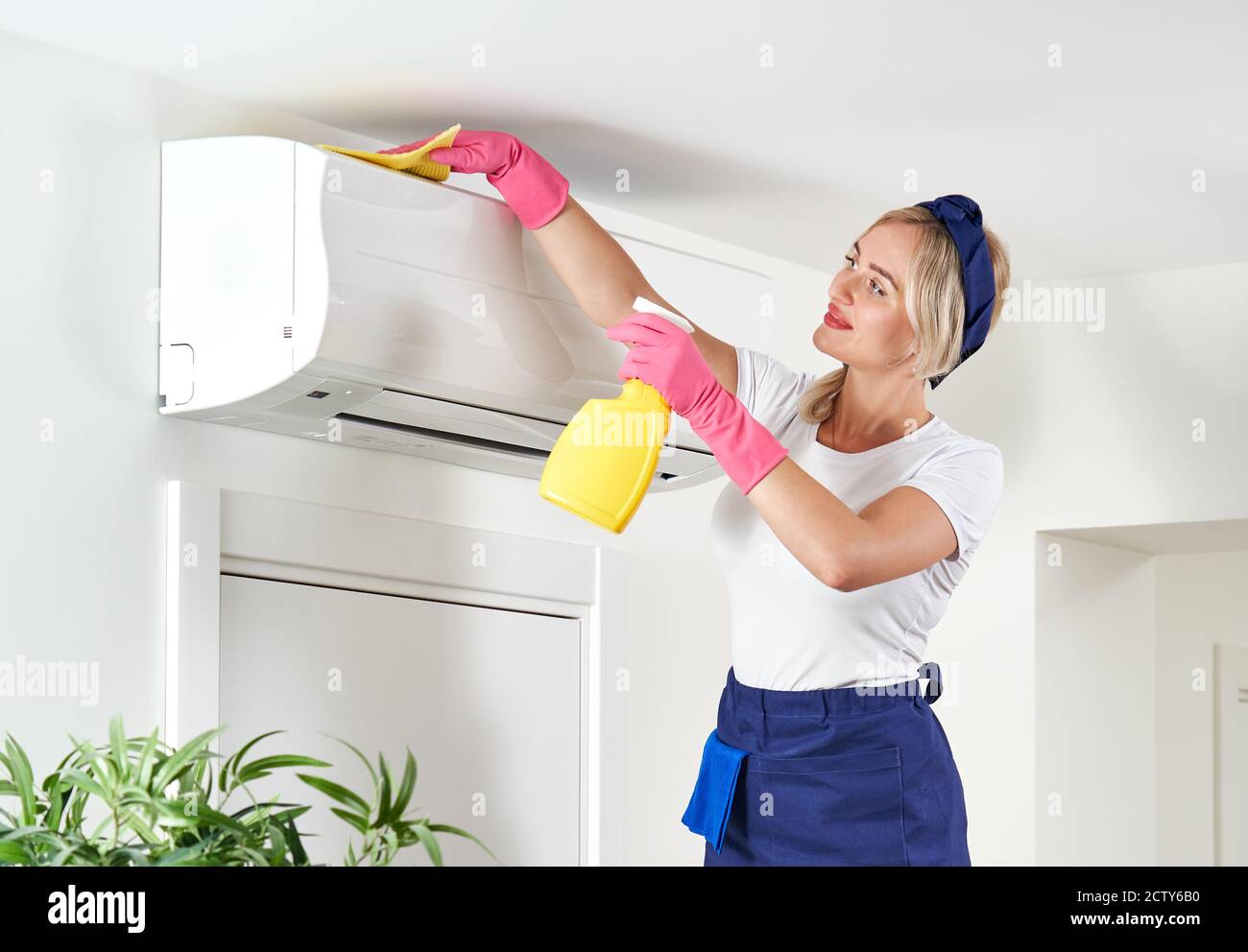 Woman cleaning air conditioner with rag. Cleaning service or housewife concept Stock Photo