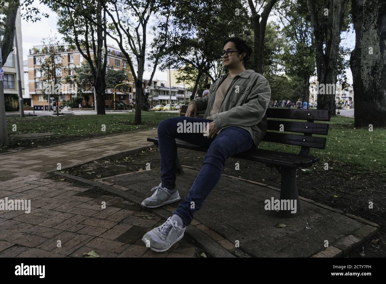 Young Hispanic man sitting on a bench and having a rest Stock Photo