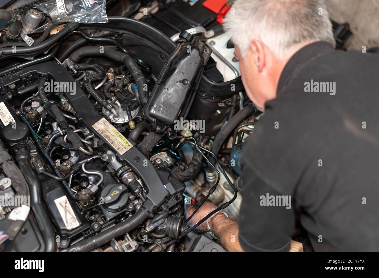 Senior Mechanic working on engine bay repairing a oil leak in home