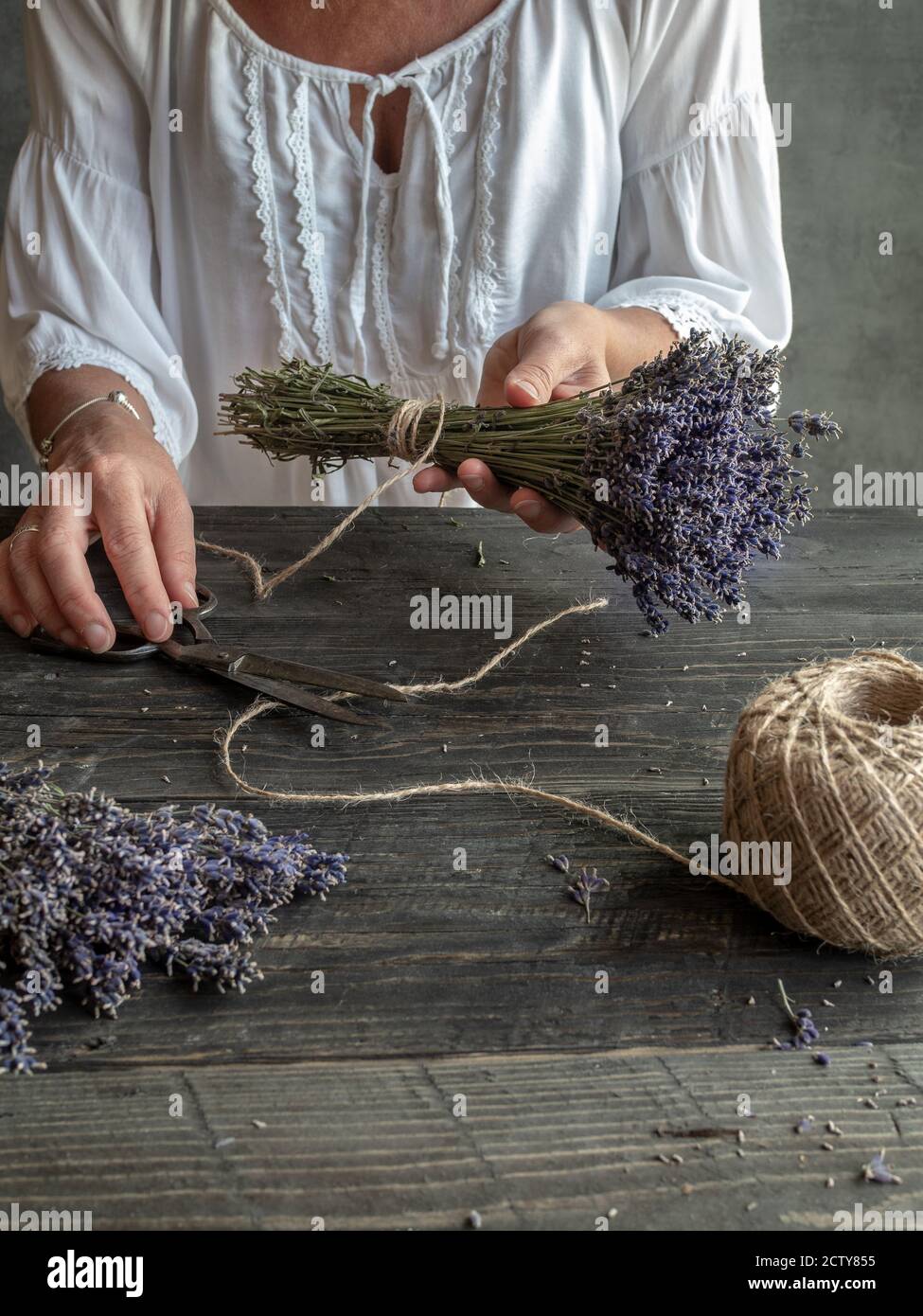 Female florist s in white shirt tied up bunch of lavender by twine