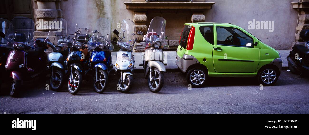 Motor scooters with a car parked in a street, Florence, Italy Stock