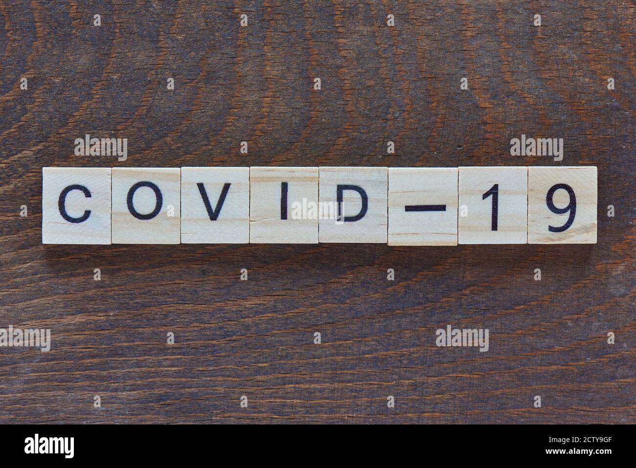 written 'COVID-19' with light wood letters on dark wood Stock Photo
