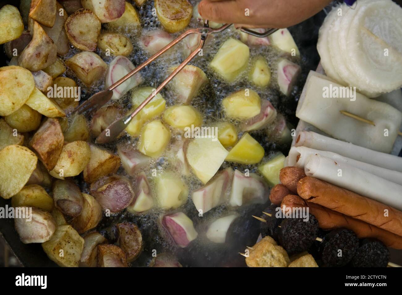 Fried potatoes and snacks on the grill in a street market, Old Town, Lijiang, Yunnan Province, China Stock Photo