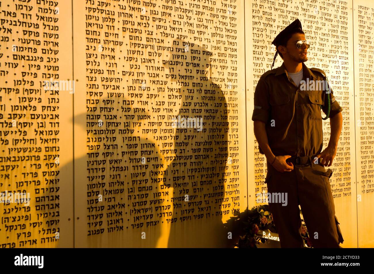 Army soldier standing in front of the Wall of Names memorial to fallen soldiers, Armored Corps Memorial, Latrun, Ayalon Valley, Shephelah, Israel Stock Photo