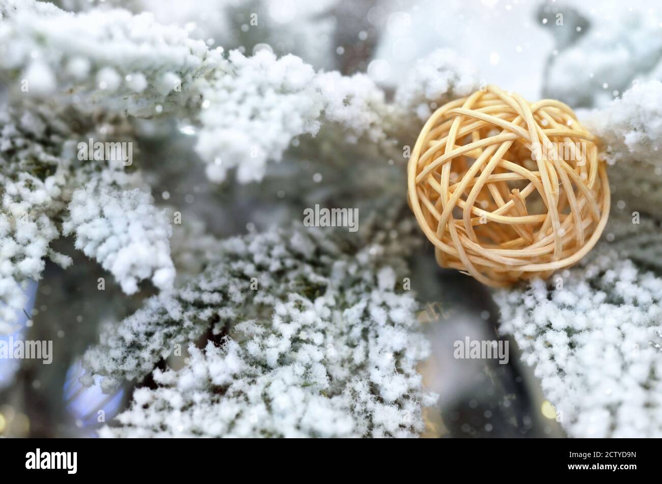 Wicker ball decoration on snow covered Christmas tree with copy space. Close-up, selective focus. Stock Photo