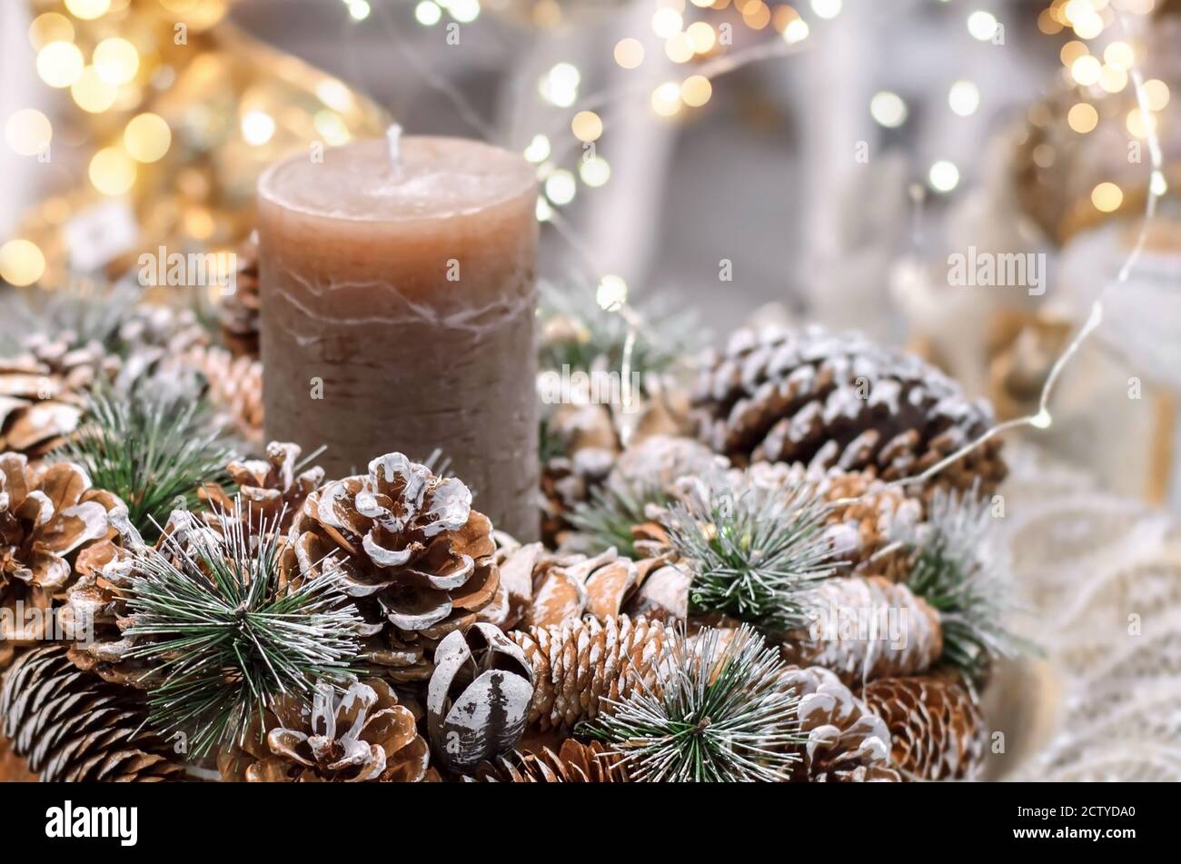 Christmas decoration with pine cones, fir branches, candle and Christmas lights. Close-up, selective focus. Stock Photo