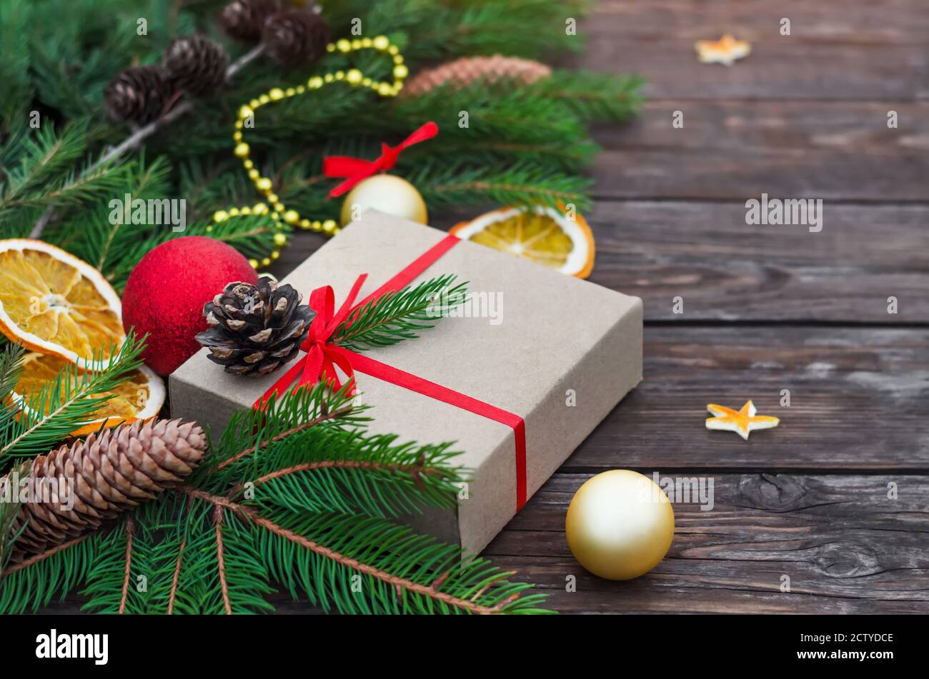 Christmas or New Year composition. Gift box with fir branches, cones and decorations on a vintage wooden background. Close-up, selective focus Stock Photo