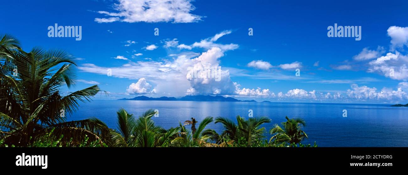 Indian ocean with palm trees towards Mahe Island looking from North Island, Seychelles Stock Photo