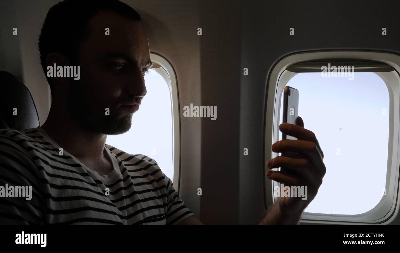 Man take funny selfie travelling in the airplane. Stock Photo