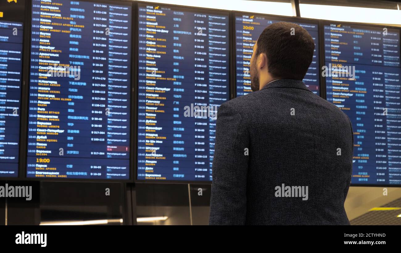 Passenger looking at timetable board screen at the airport, inte Stock Photo