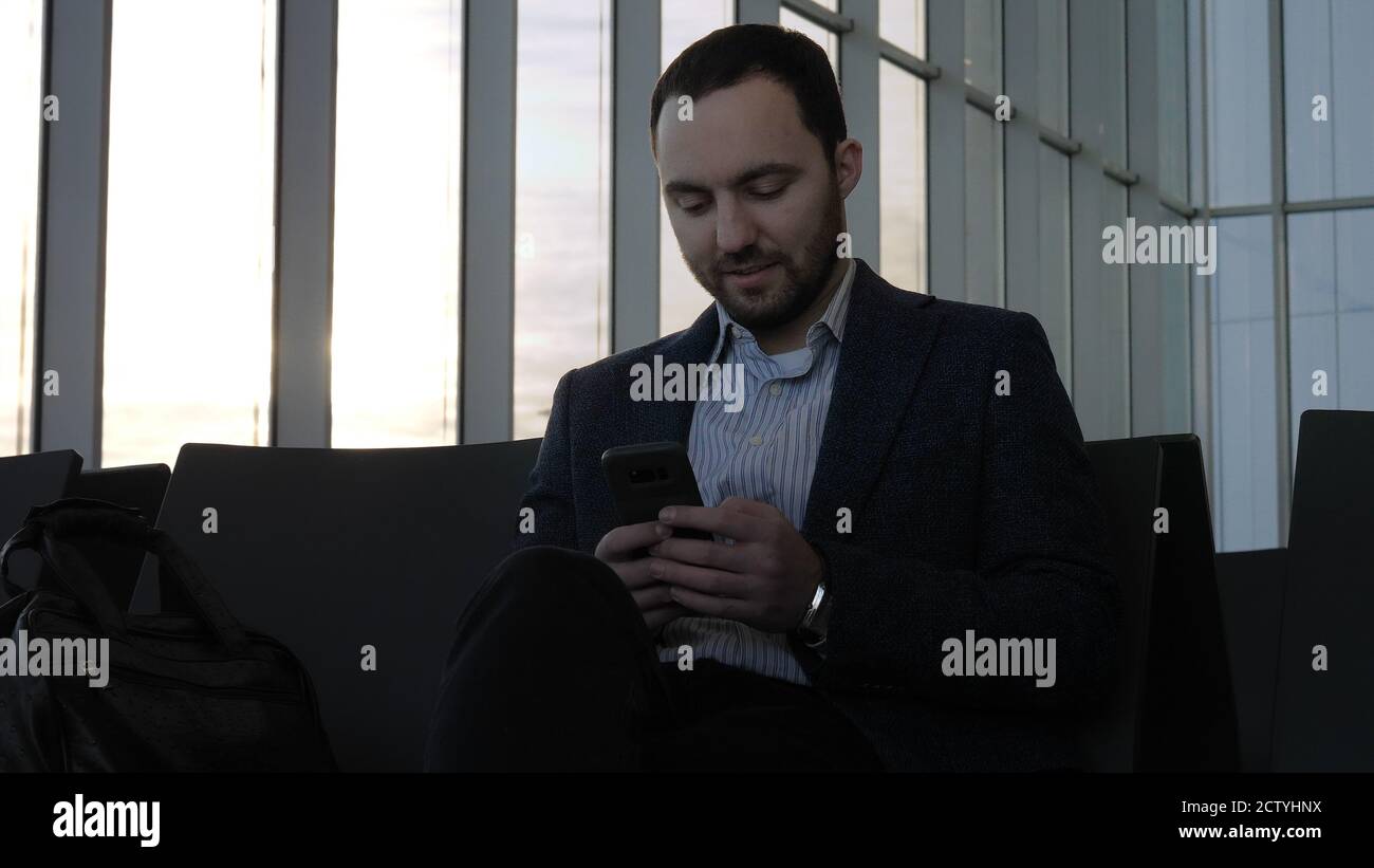 Business man messaging through his mobile phone while sitting in Stock Photo
