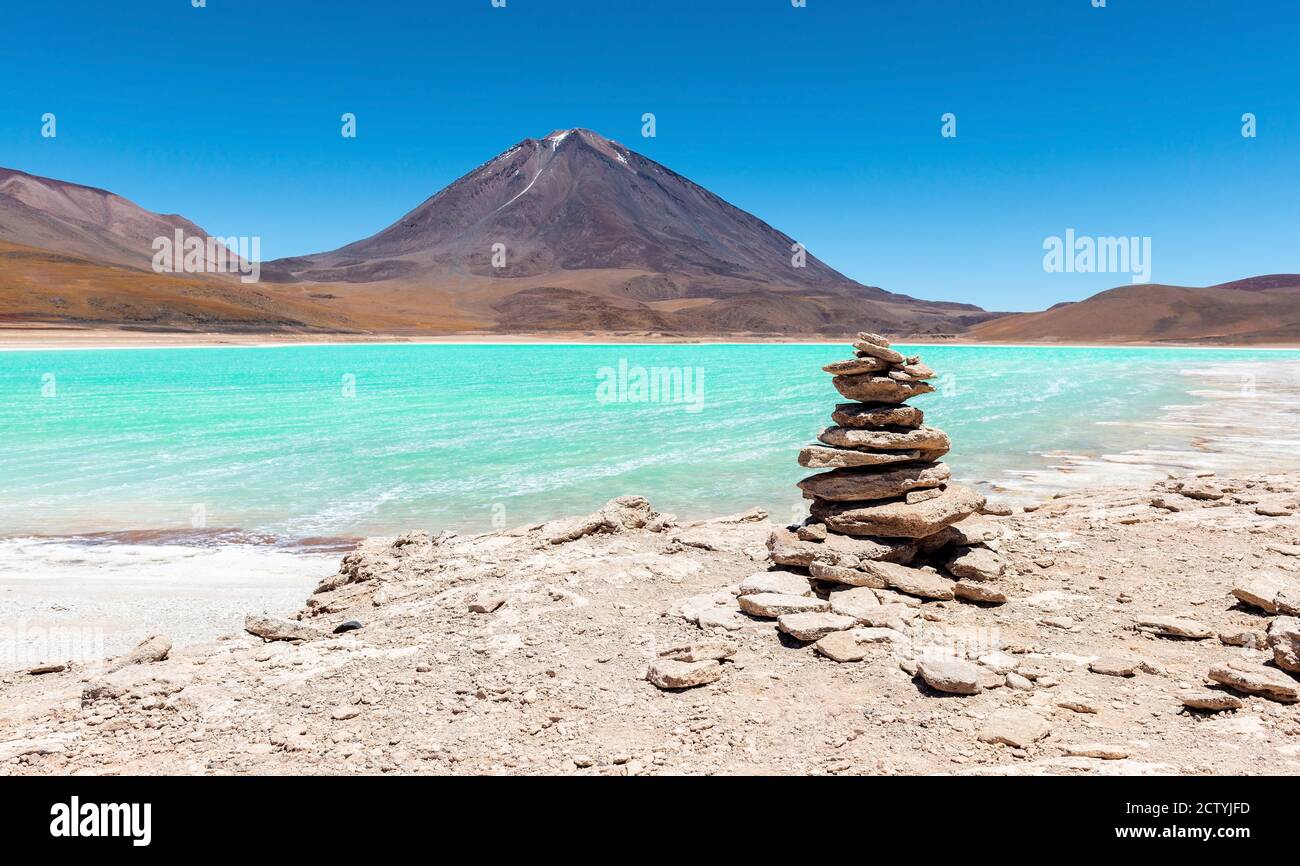Panorama of a wish stone pyramid by the Laguna Verde (green lagoon) and the Licancabur volcano, Bolivia. Stock Photo