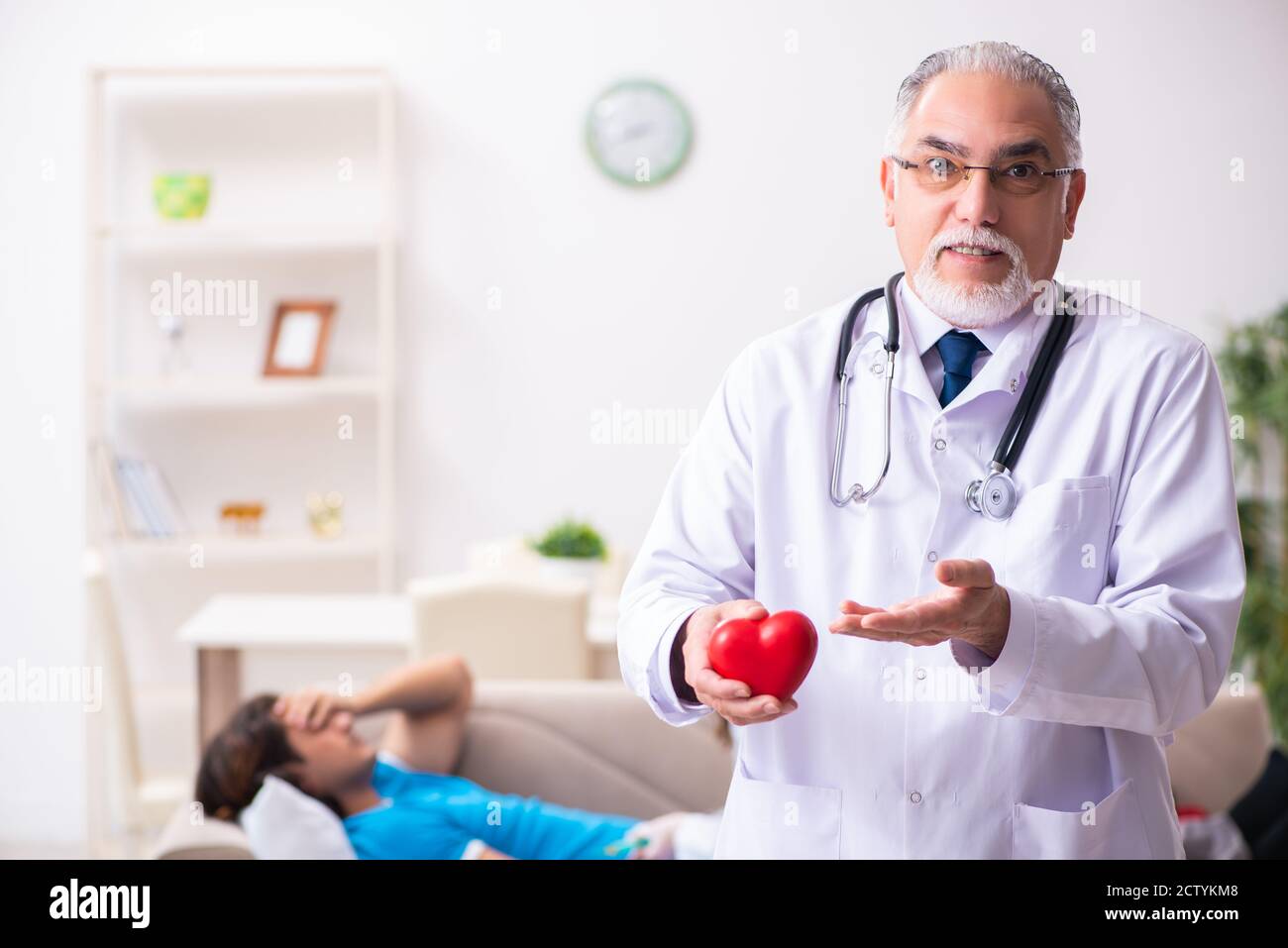 Two doctors visiting sick man at home Stock Photo