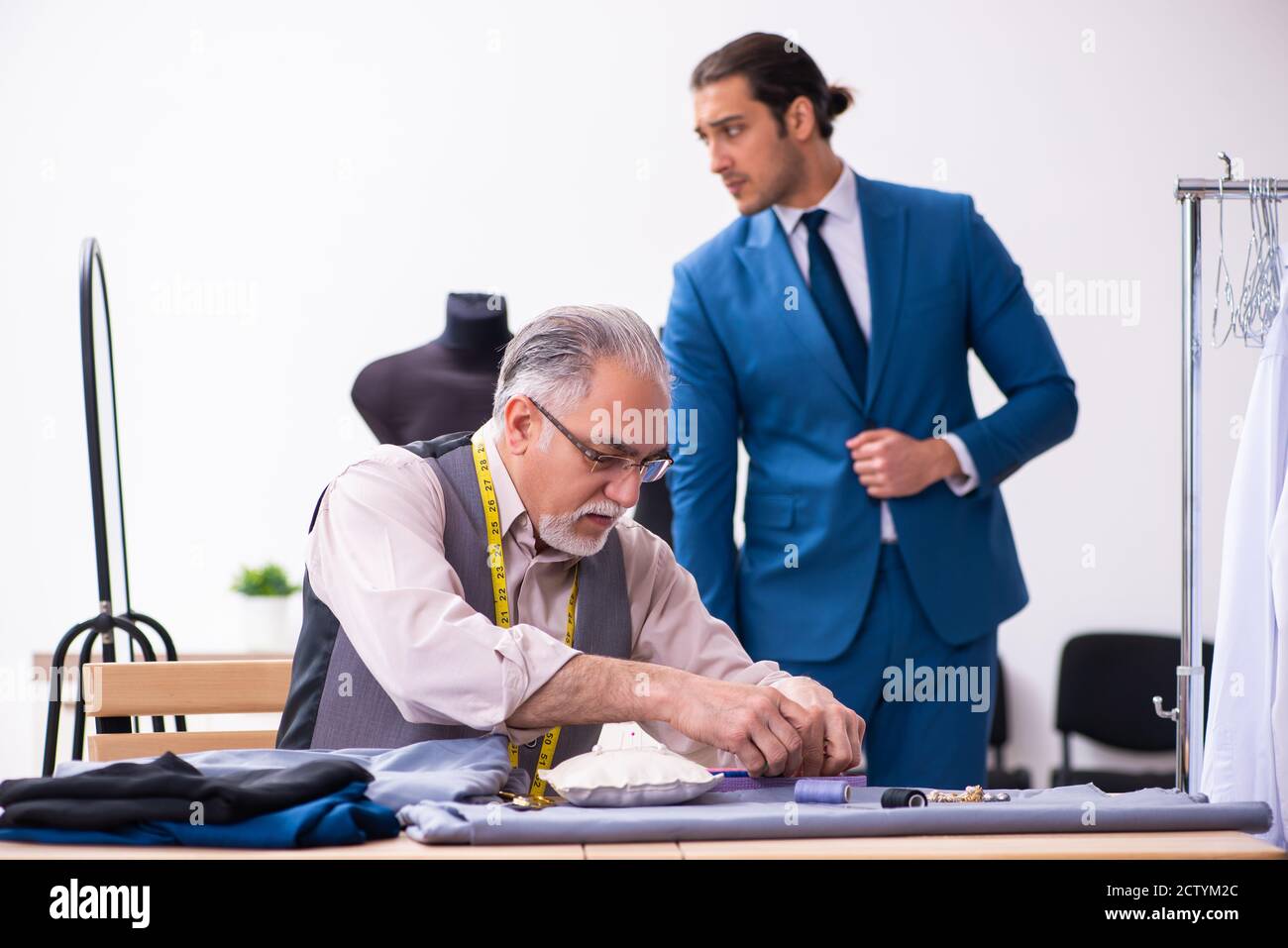 Young businessman visiting old tailor Stock Photo