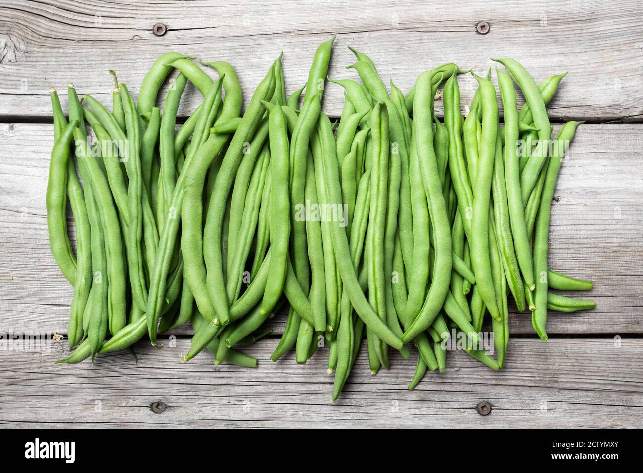 Many green bean pods on aged wood bench. Beautiful top view arrangement of  home grown blue lake pole bean harvest. Concept for self-sufficient garden Stock Photo