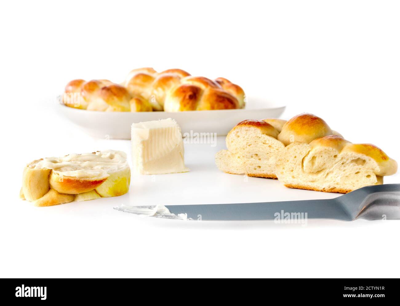Multiple small braided buns, whole and sliced, with butter and knife. Concept for traditional breakfast table. Authentic Swiss butter bread recipe. Stock Photo