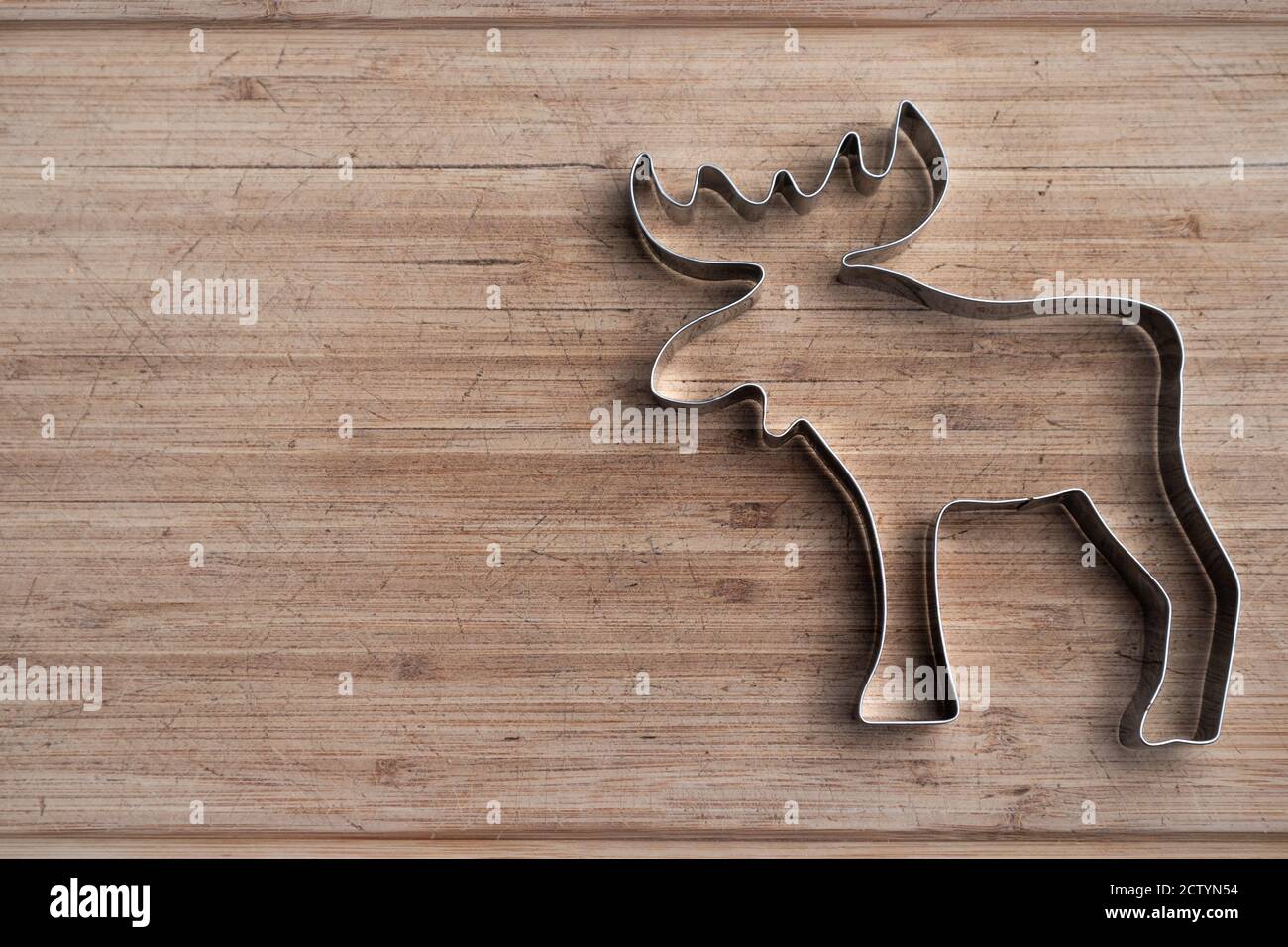 Stainless steel moose shape on wood board. Animal cookie cutter. Patriotic symbol of Canada. Silver silhouette. Copy space. Stock Photo