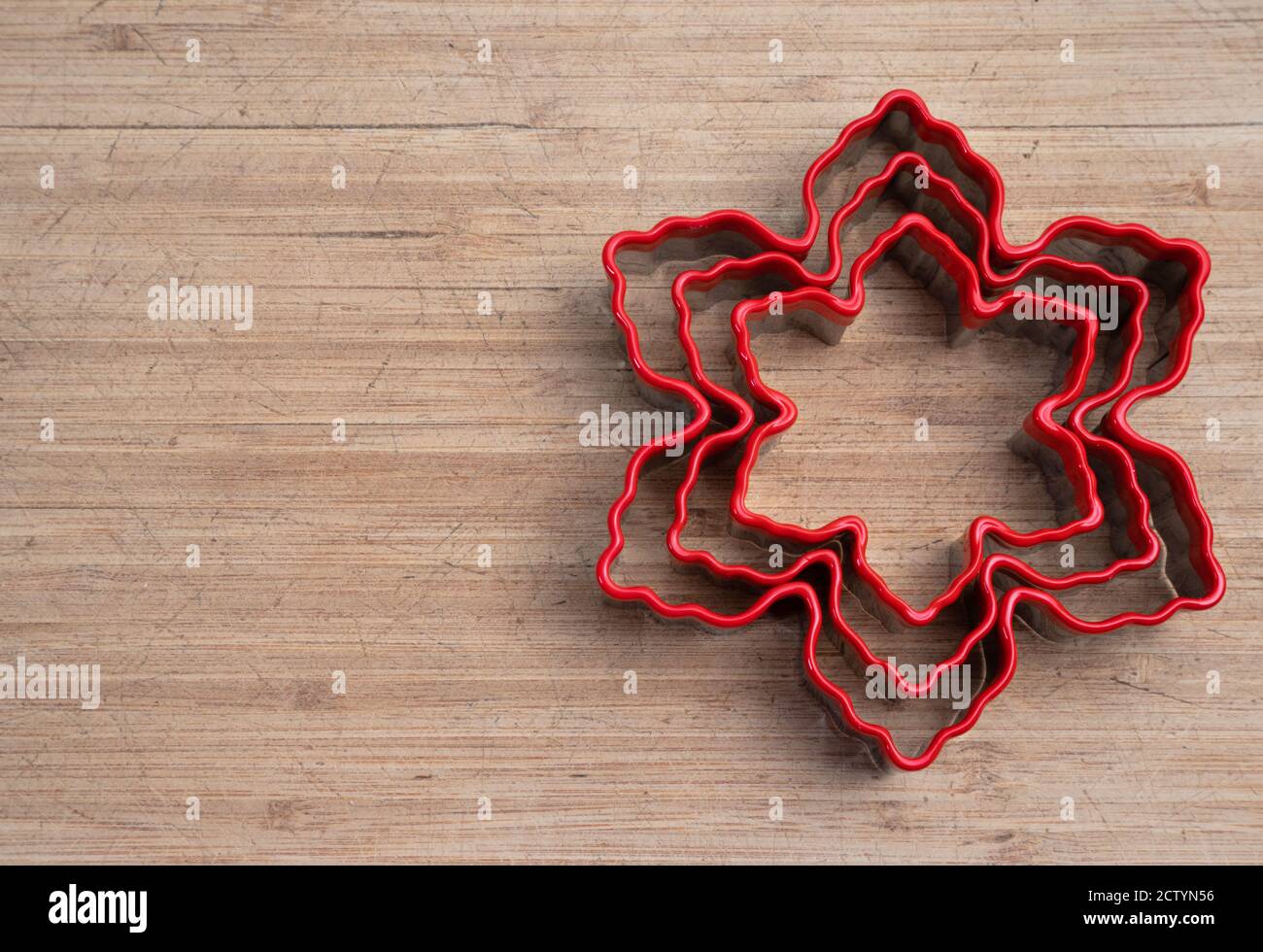 Red snowflake cookie cutter on wood cutting board. Holiday concept. Copy space. Stock Photo
