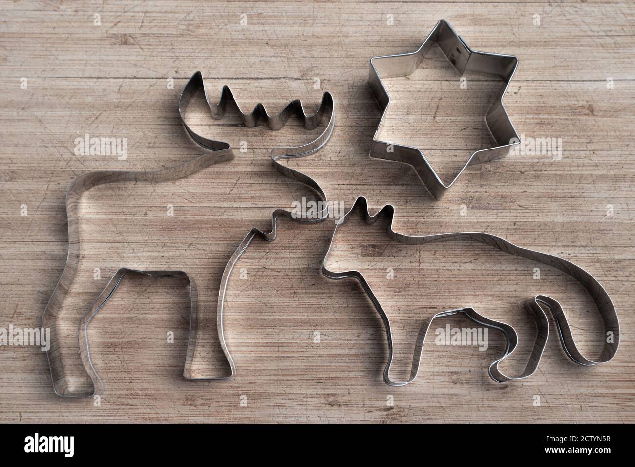 Stainless steel wild animal shapes on wood board. Moose, fox and star cookie cutter. Patriotic symbol of Canada. Silver silhouette. Stock Photo
