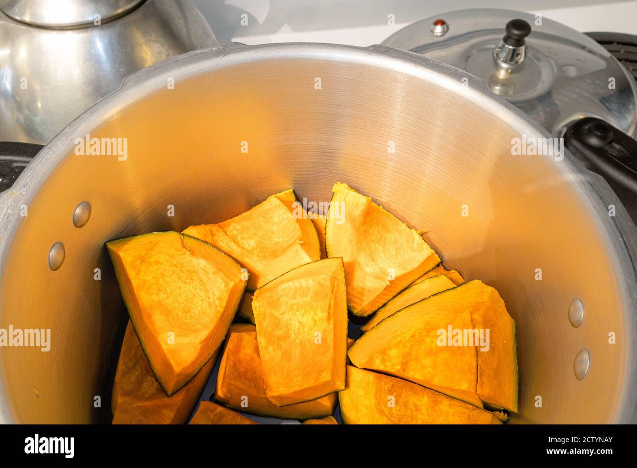 Buttercup squash pieces inside pressure cooker. Kabocha squash, turban squash or  Cucurbita maxima. Orange sweet flesh, high on vitamine a and fiber. Stock Photo