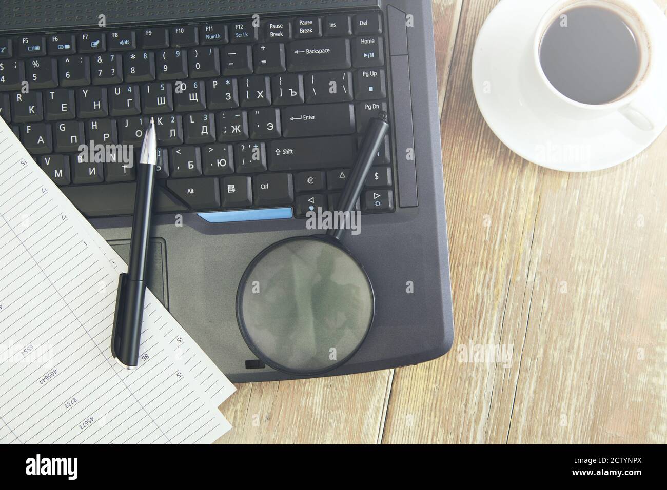 Office workplace with laptop, papers and magnifying glass on wood table ...