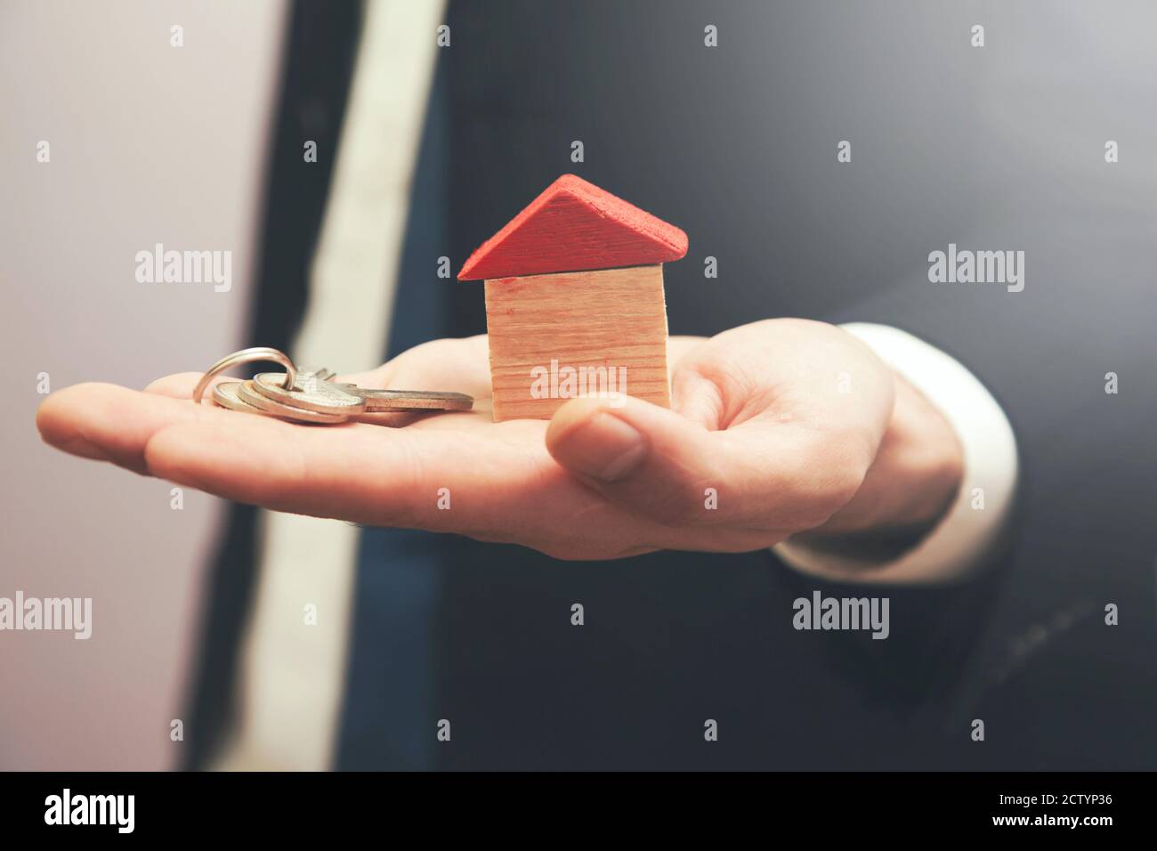 real estate agent holding a wooden house and key in his hand Stock ...