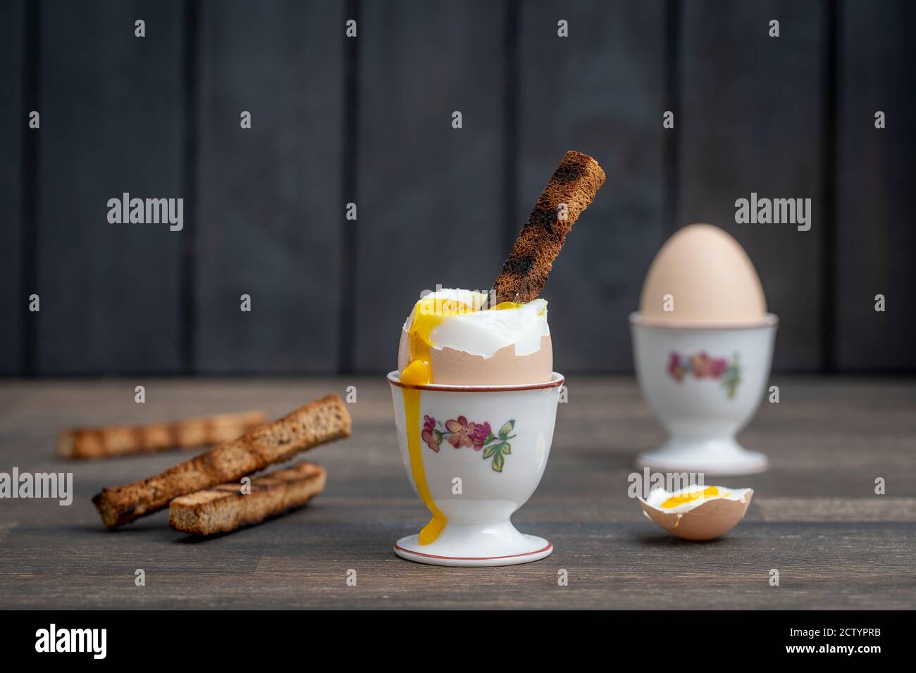 Soft boiled brown egg and toast bread in eggcup on wooden table background. Close up. Healthy breakfast Stock Photo
