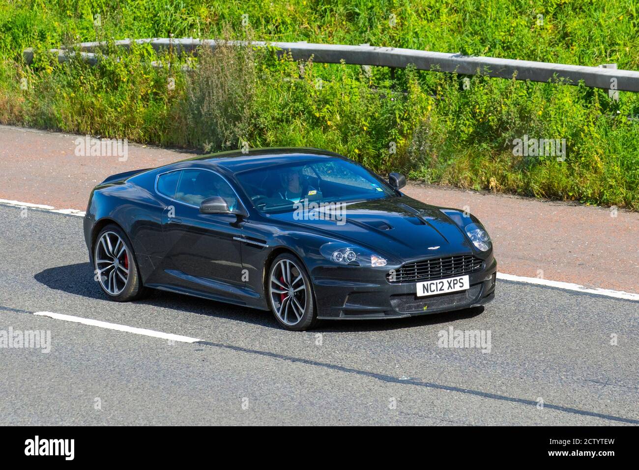 2012 5935cc black Aston Martin DBS V12 Superleggera Touchtronic 5.2 Automatic 2 door Coupe; Vehicular traffic moving vehicles, supercars, vehicle driving on UK roads, motors, motoring on the M6 motorway highway road network. Stock Photo