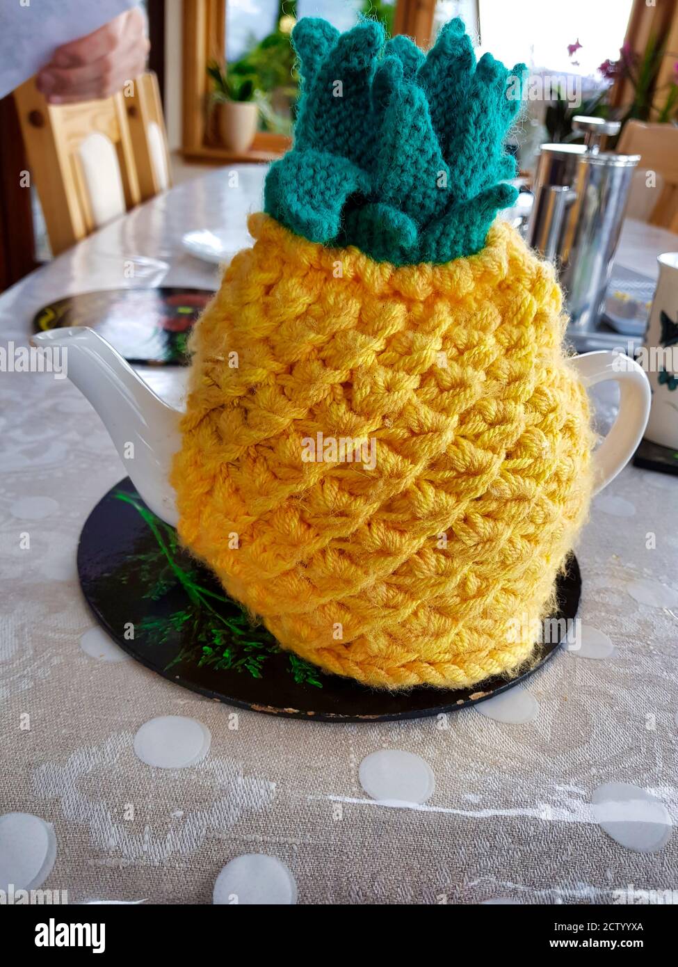 knitted pineapple is used as a tea warmer for a teapot Stock Photo