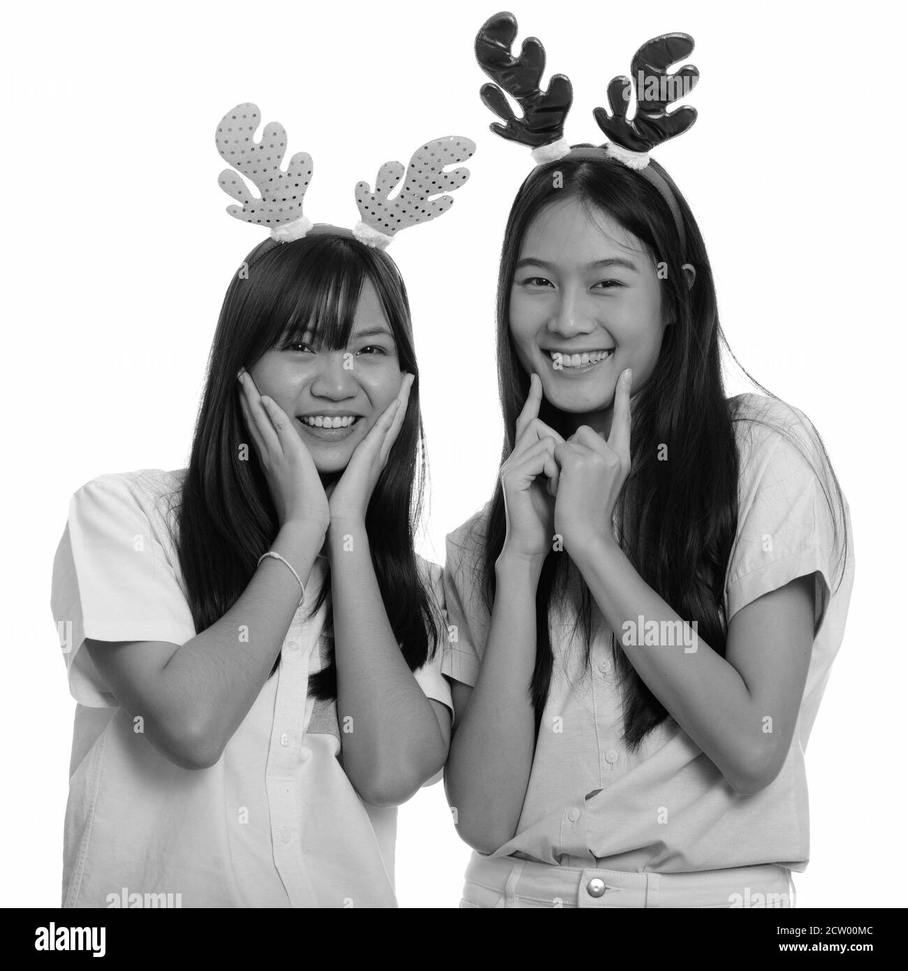 Two young happy Asian teenage girls smiling and posing ready for Christmas Stock Photo