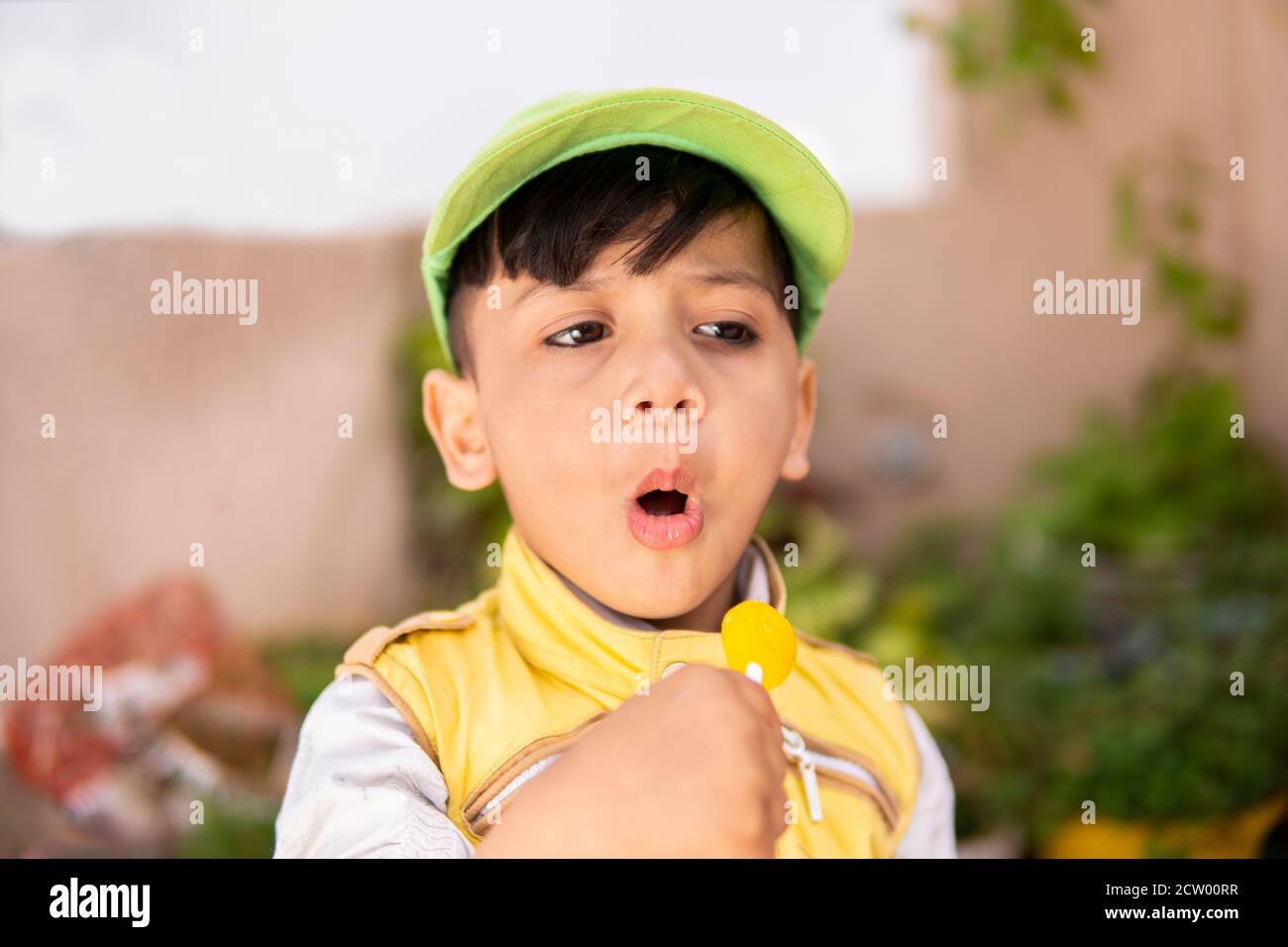Cut little boy eating lollipop candy and having fun in outdoor at day time. Stock Photo