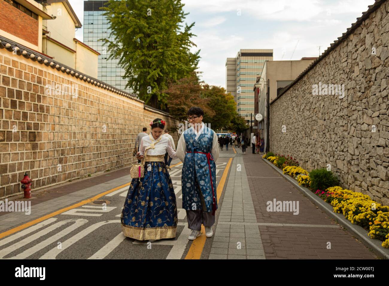 Seoul, South Korea - October 19th 2017: A Korean couple in traditional hanbok dress walking along an alley at sunset, Seoul, South Korea Stock Photo
