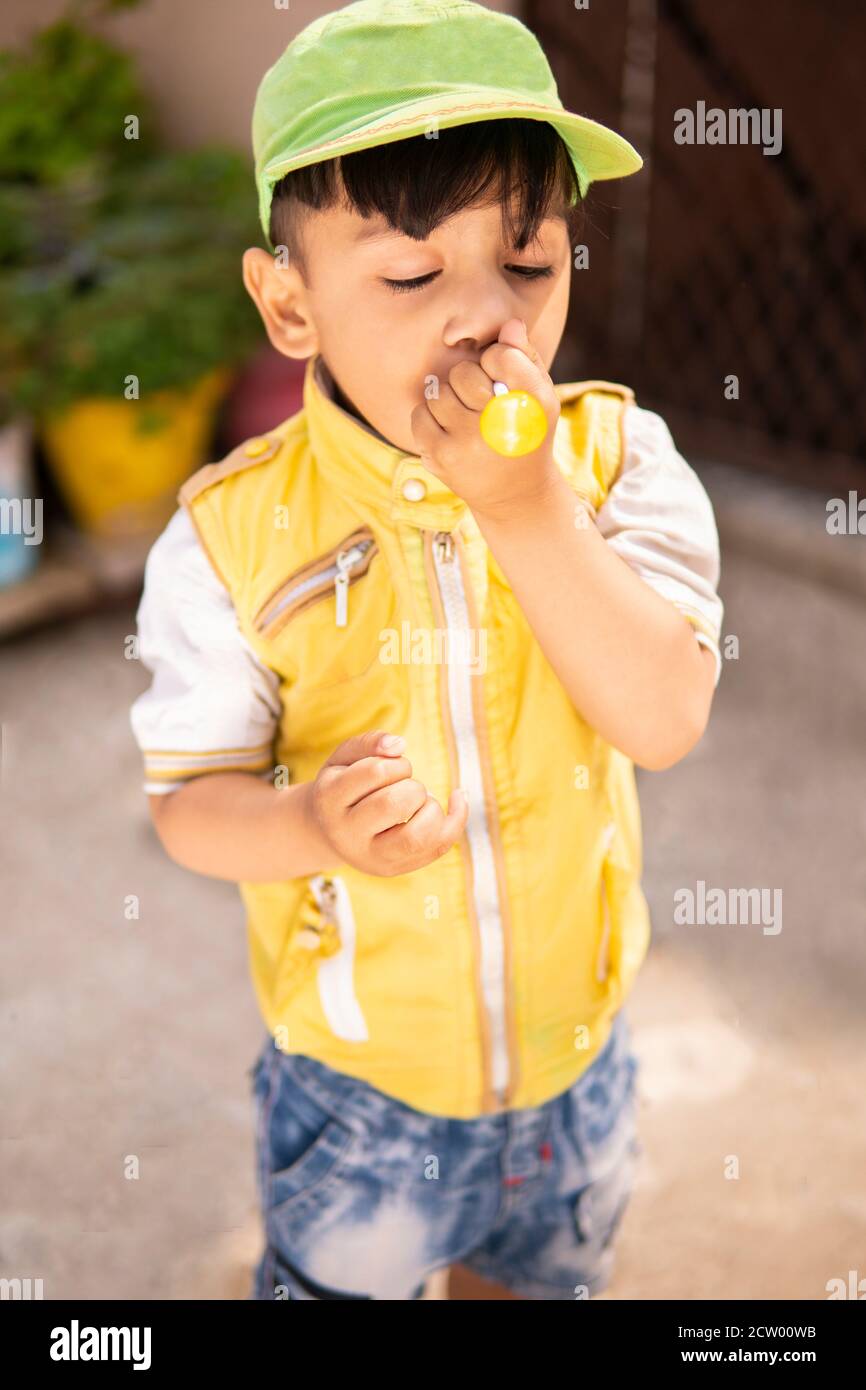 Cut little boy eating lollipop candy and having fun in outdoor at day time. Stock Photo