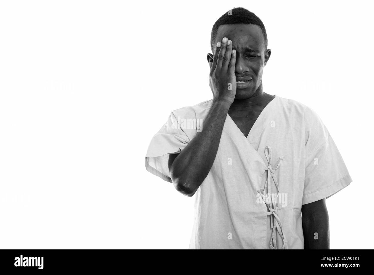 Studio shot of young black African man patient looking sad while covering face Stock Photo
