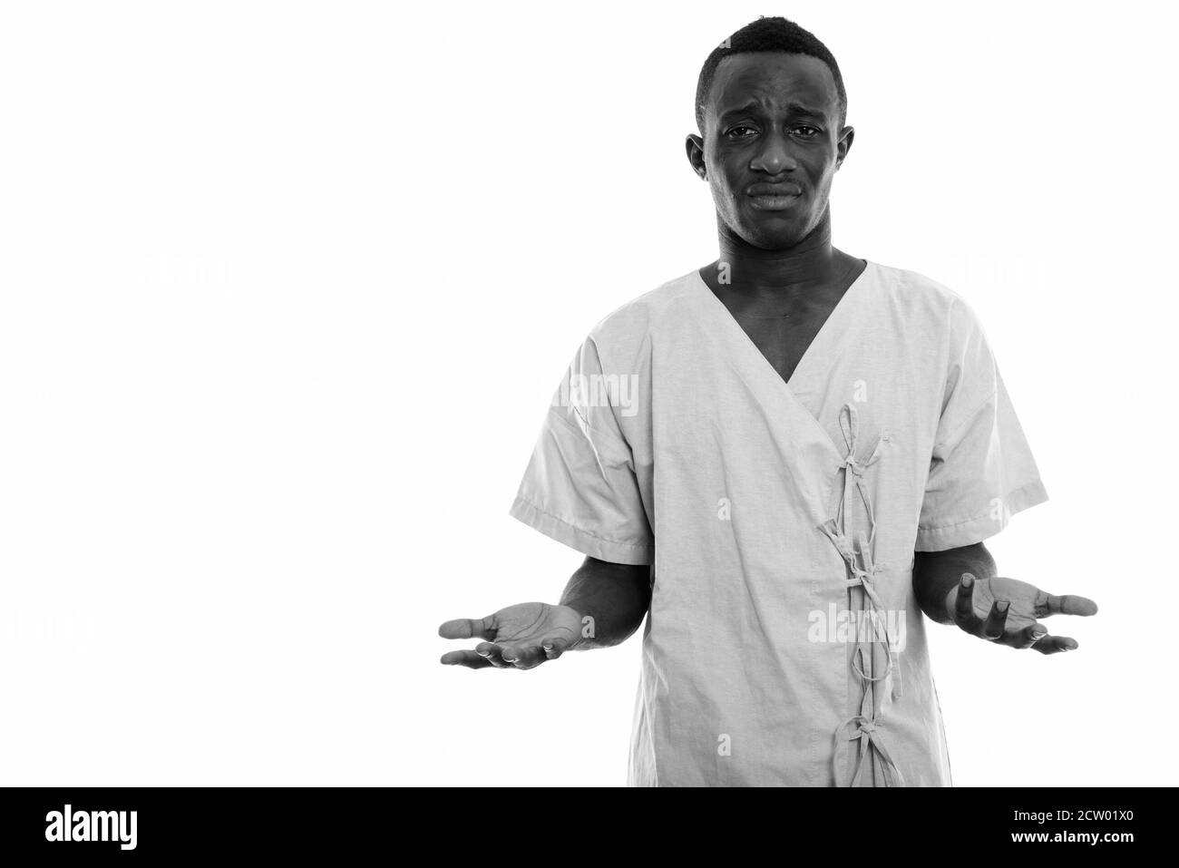 Studio shot of young stressed black African man patient looking confused while shrugging shoulders Stock Photo