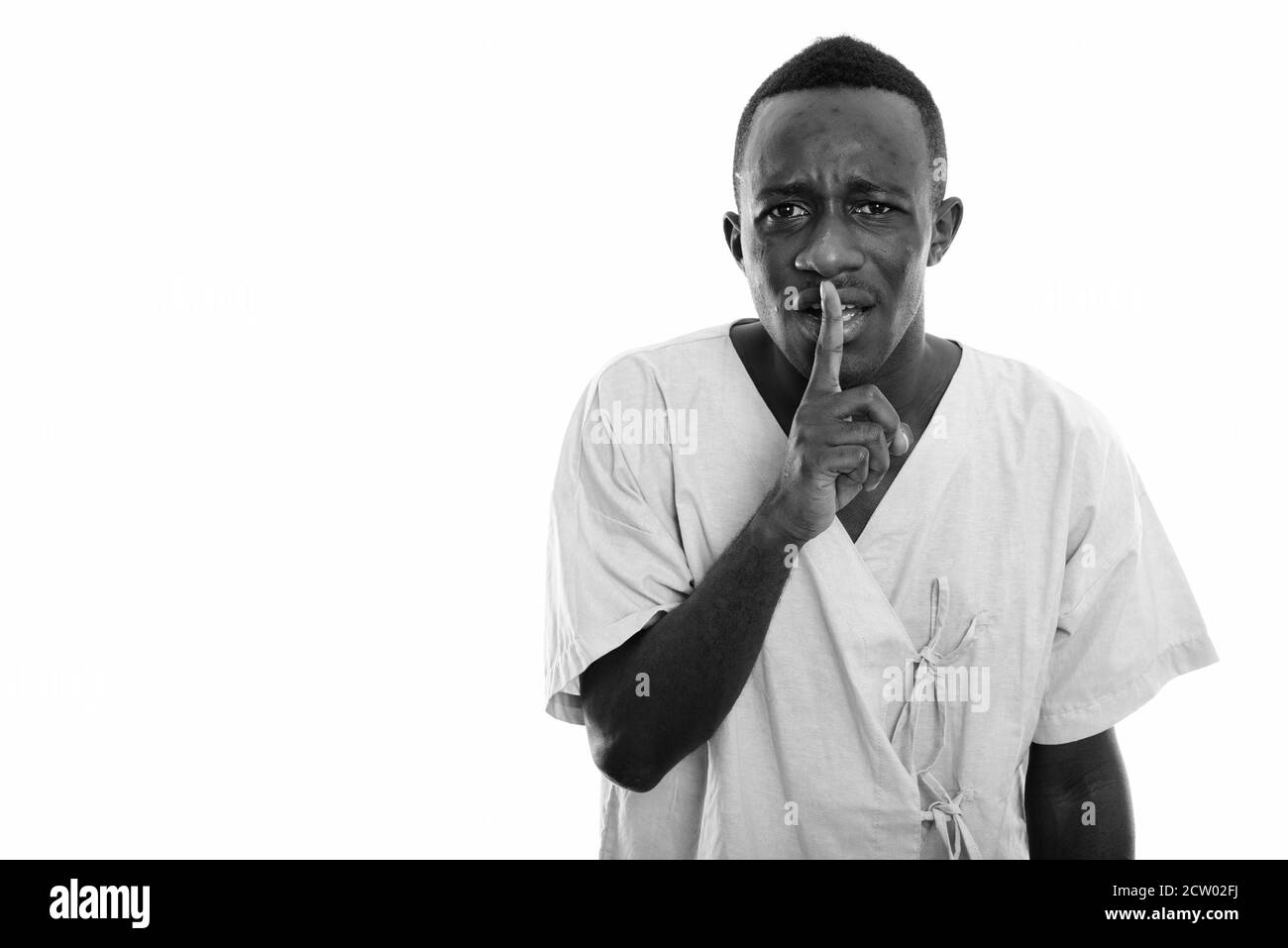 Studio shot of young black African man patient with finger on lips Stock Photo