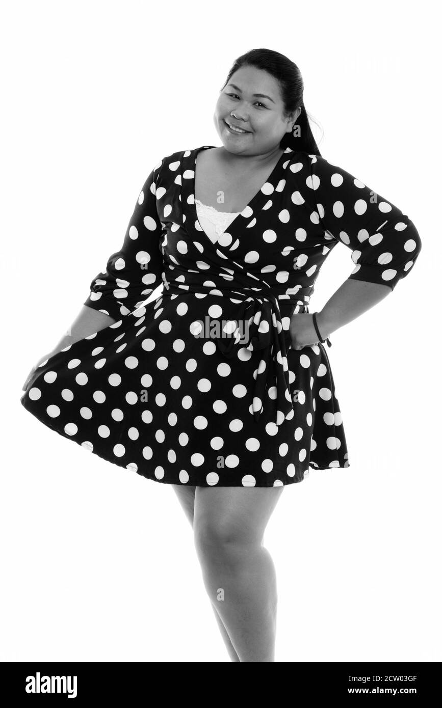 Studio shot of young happy fat Asian woman smiling while standing and holding dress Stock Photo