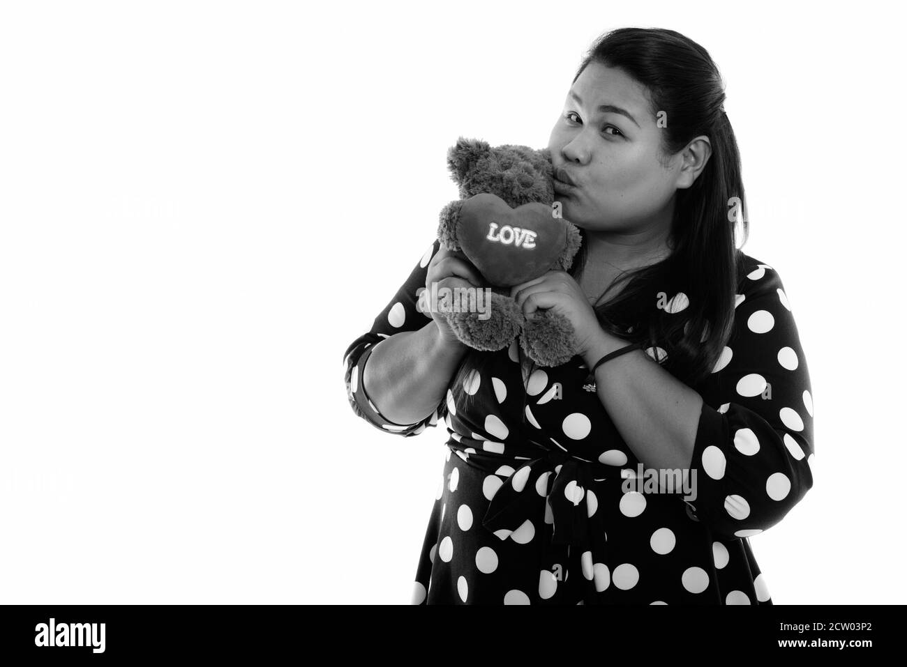 Studio shot of young fat Asian woman holding and kissing teddy bear with heart and love sign Stock Photo