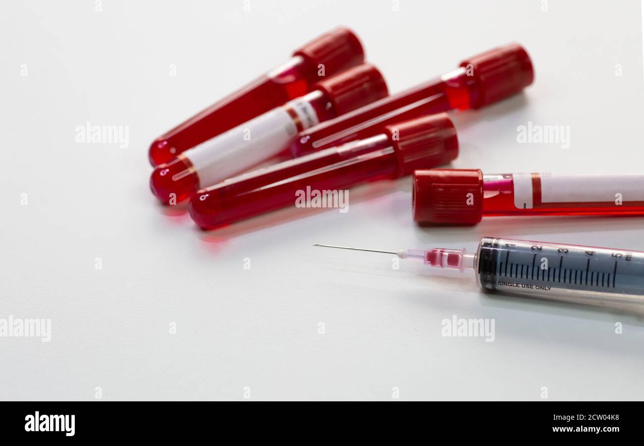 Injection syringe with blood sample vials of patients and vaccine bottles on white background Stock Photo