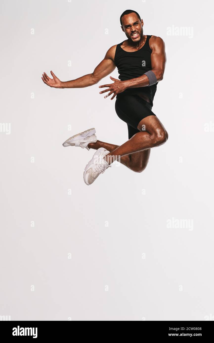 African american athlete doing fitness exercise. Fit man jumping high in air during workout. Stock Photo