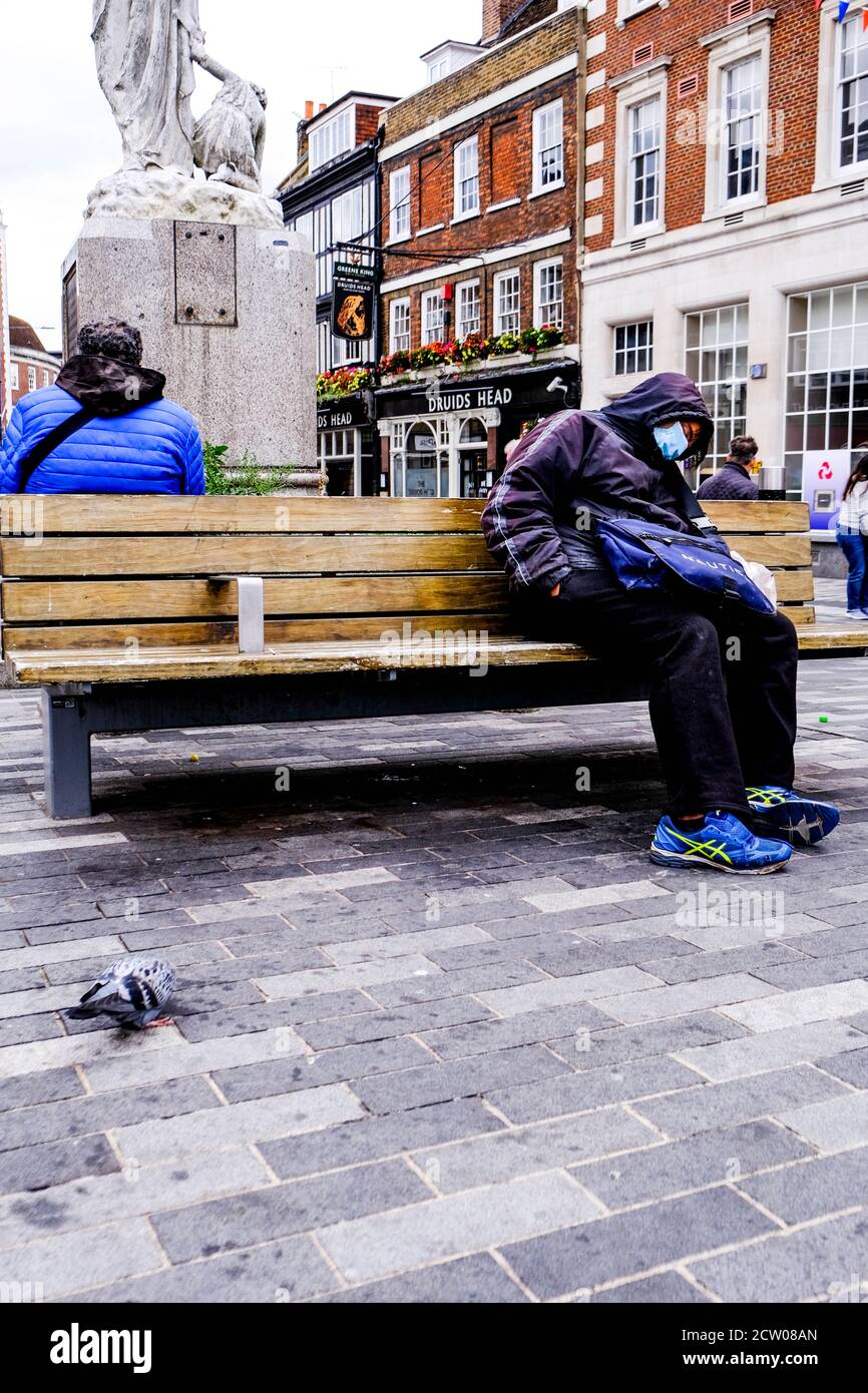 Homeless Person Sleeping Town Centrre Bench Wearing Face Covering During COVID-19 Stock Photo