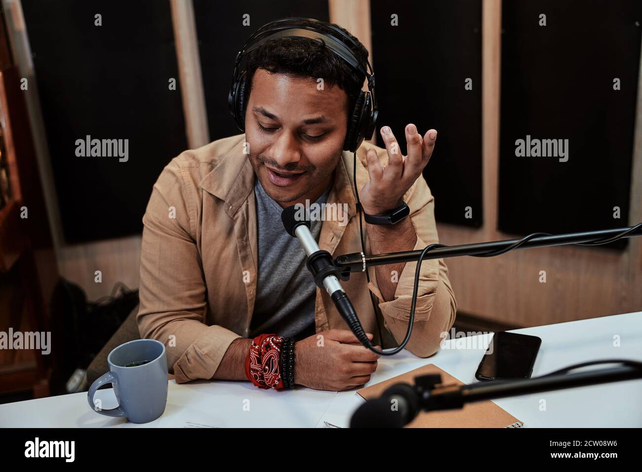 Happy young male radio host talking, broadcasting in studio using microphone and headphones Stock Photo