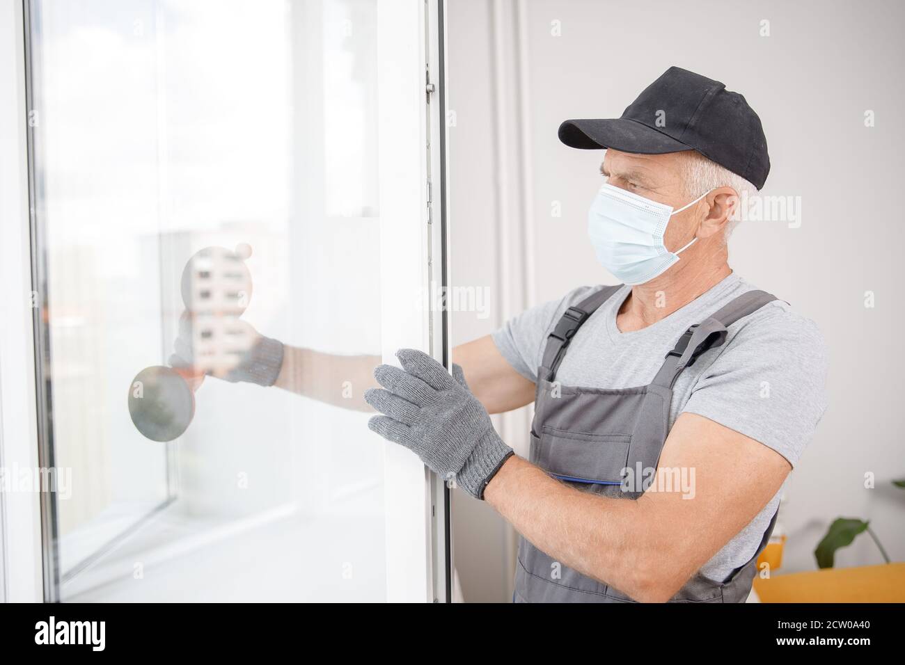 Worker man installs plastic windows and doors with double-glazed white Stock Photo
