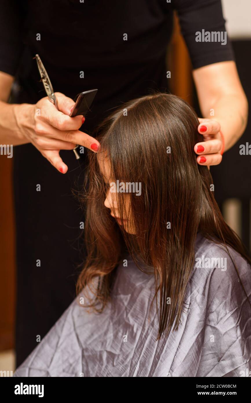 Portrait of a young girl getting her hair cut in home. Mom's hand with  hairdressing scissors. Little child sits patiently while having her haircut  Stock Photo - Alamy