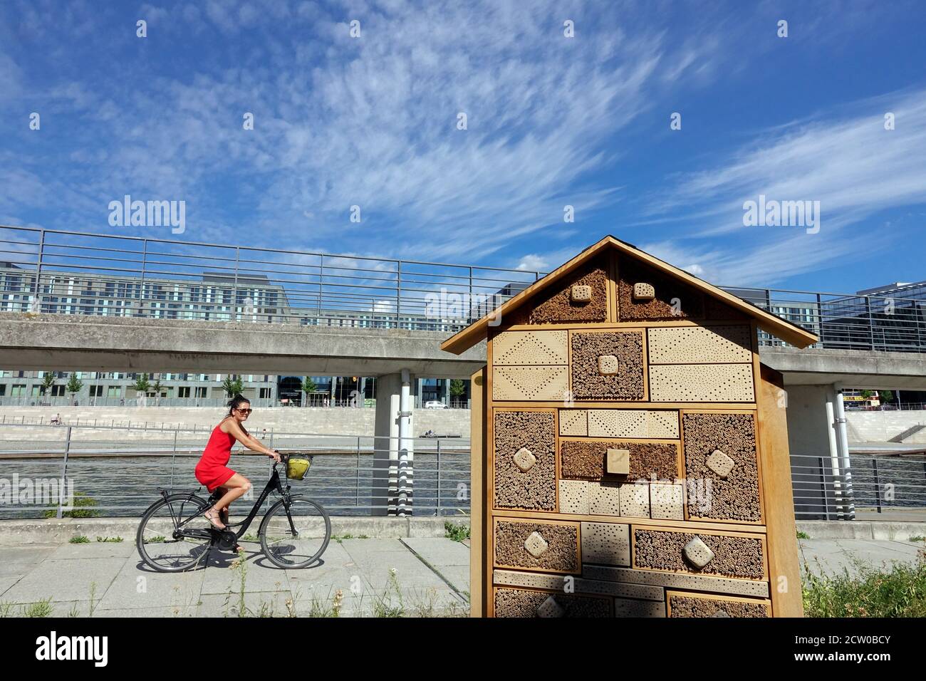 Bee hotel for solitary bees Berlin woman bike City riverside Stock Photo