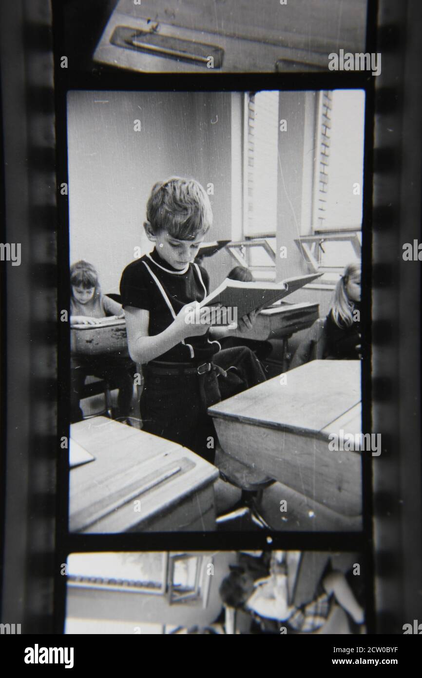 Fine 1970s vintage black and white photography of grade school students sitting in their desks and following the daily lessons. Stock Photo